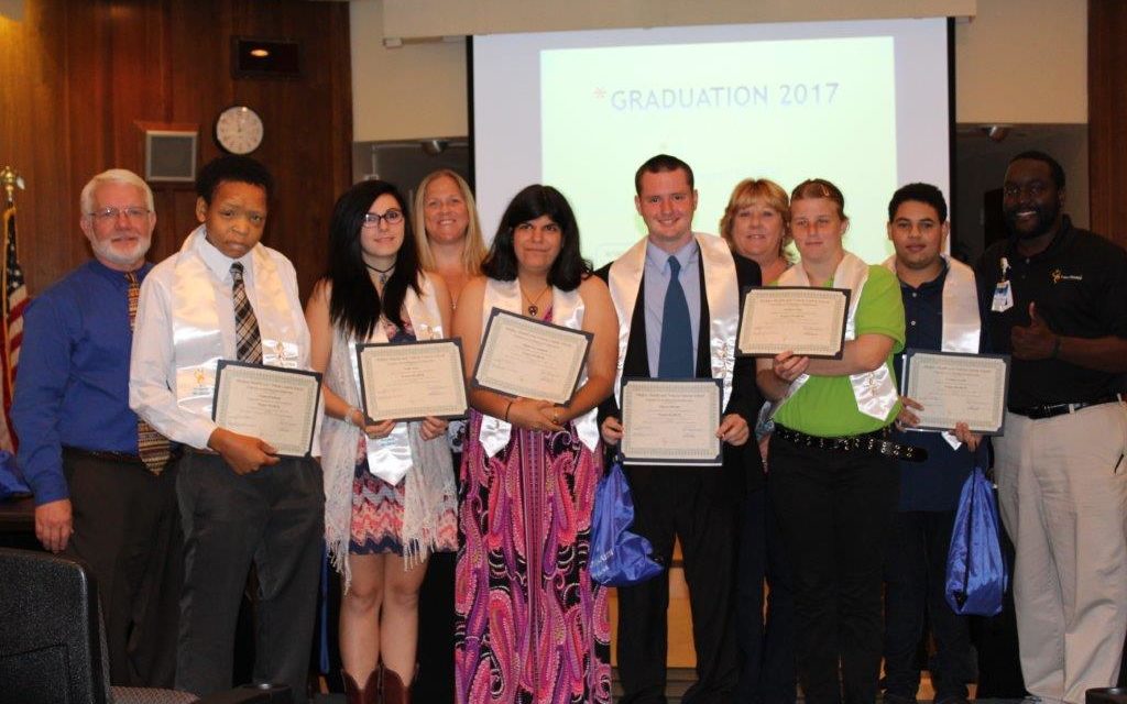 Picture of eight Project SEARCH students with High School Diplomas at Graduation Event at Halifax Health