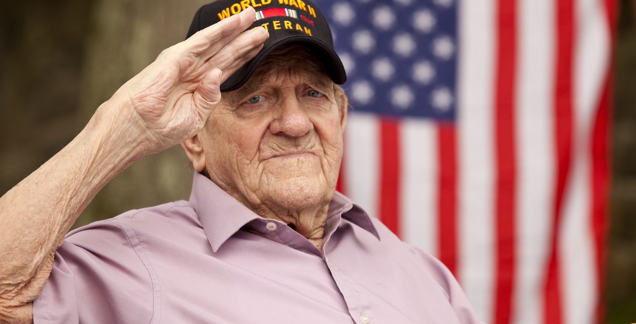 World War Two, Veteran wearing cap with text, "World War Two Veteran". Saluting