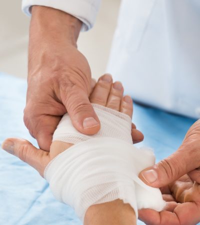 Close-up Of Person Hand Wrapping Bandage To Patient
